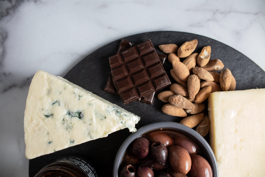 blue cheese, chocolate, almonds and olives on a cheese board